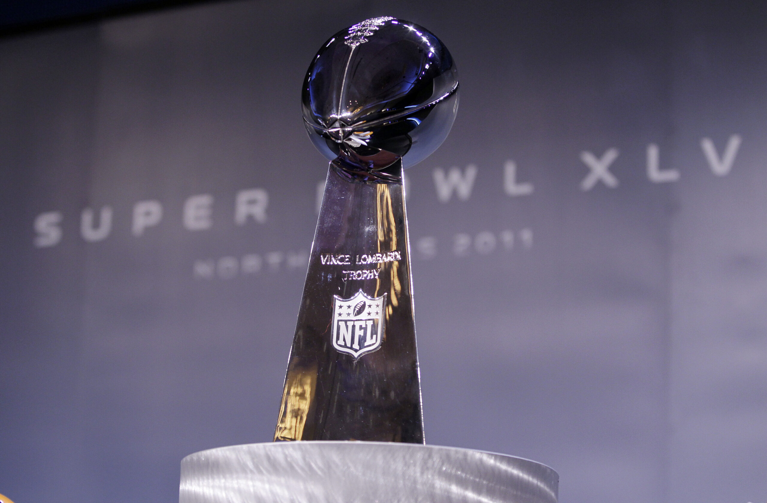 The Vince Lombardi Trophy stands between the helmets of the Pittsburgh Steelers and the Green Bay Packers at a Press Conference in Dallas
